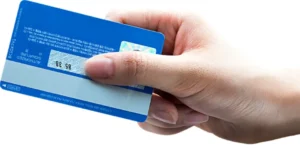 파란색 체크카드를 한 손으로 쥐고 있는 사진.