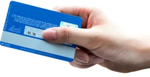 파란색 체크카드를 한 손으로 쥐고 있는 사진.